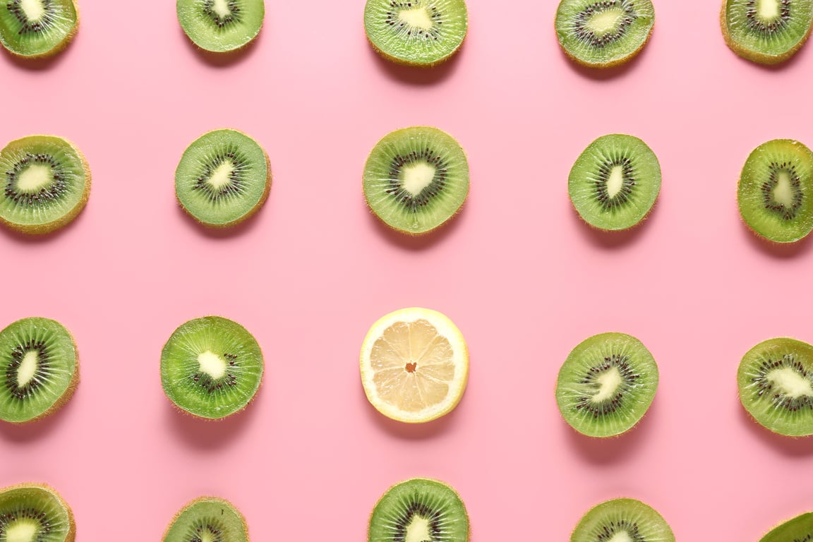 Many Slices of Kiwi and One Lemon on Color Background. Concept of Uniqueness