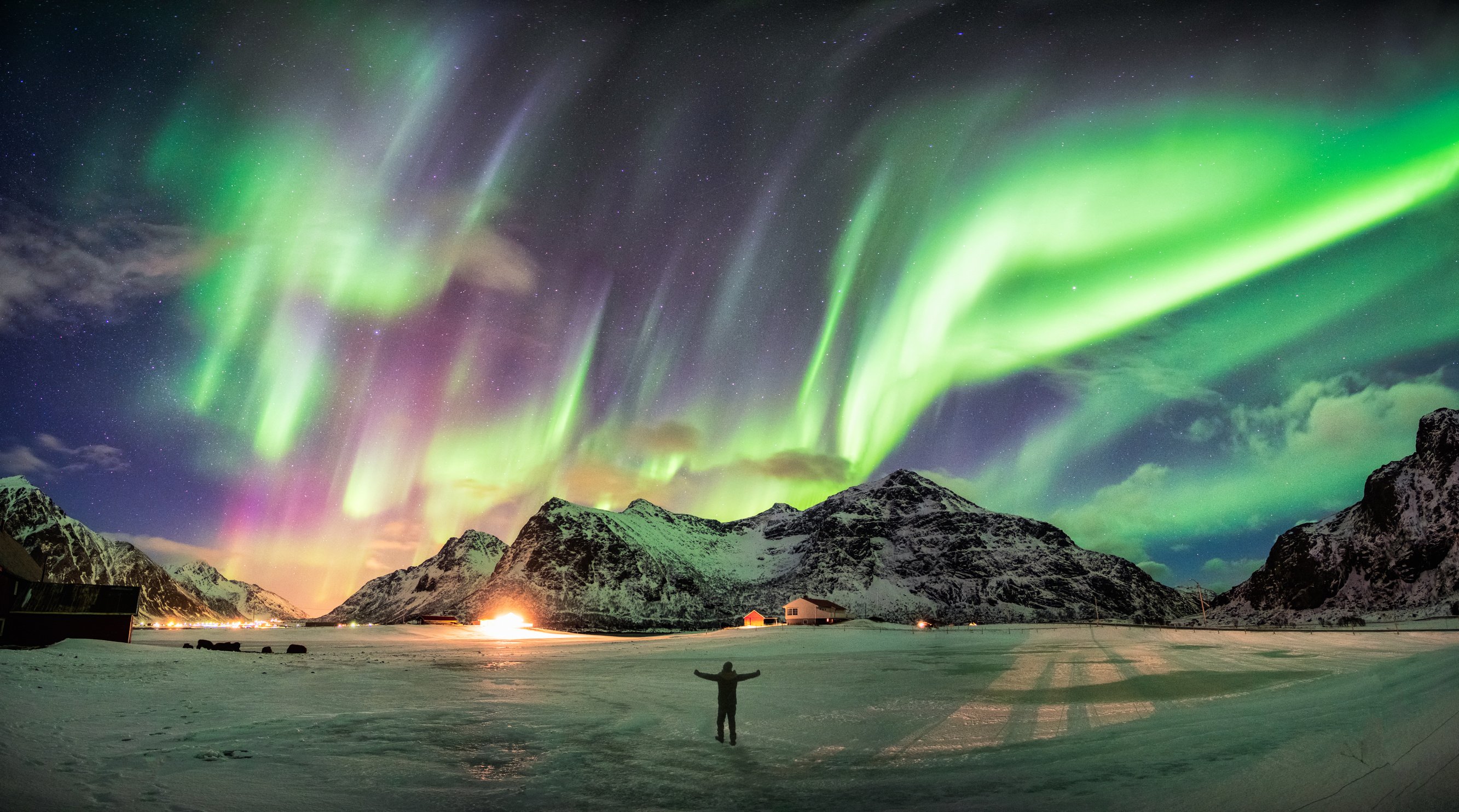 Aurora borealis (Northern lights) over mountain with one person